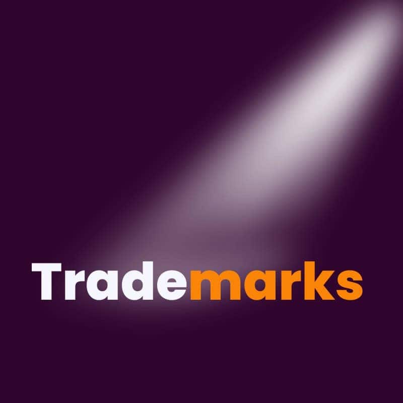 The word "trademarks" with "trade" in white and "marks" in orange, under a spotlight on a dark purple background.