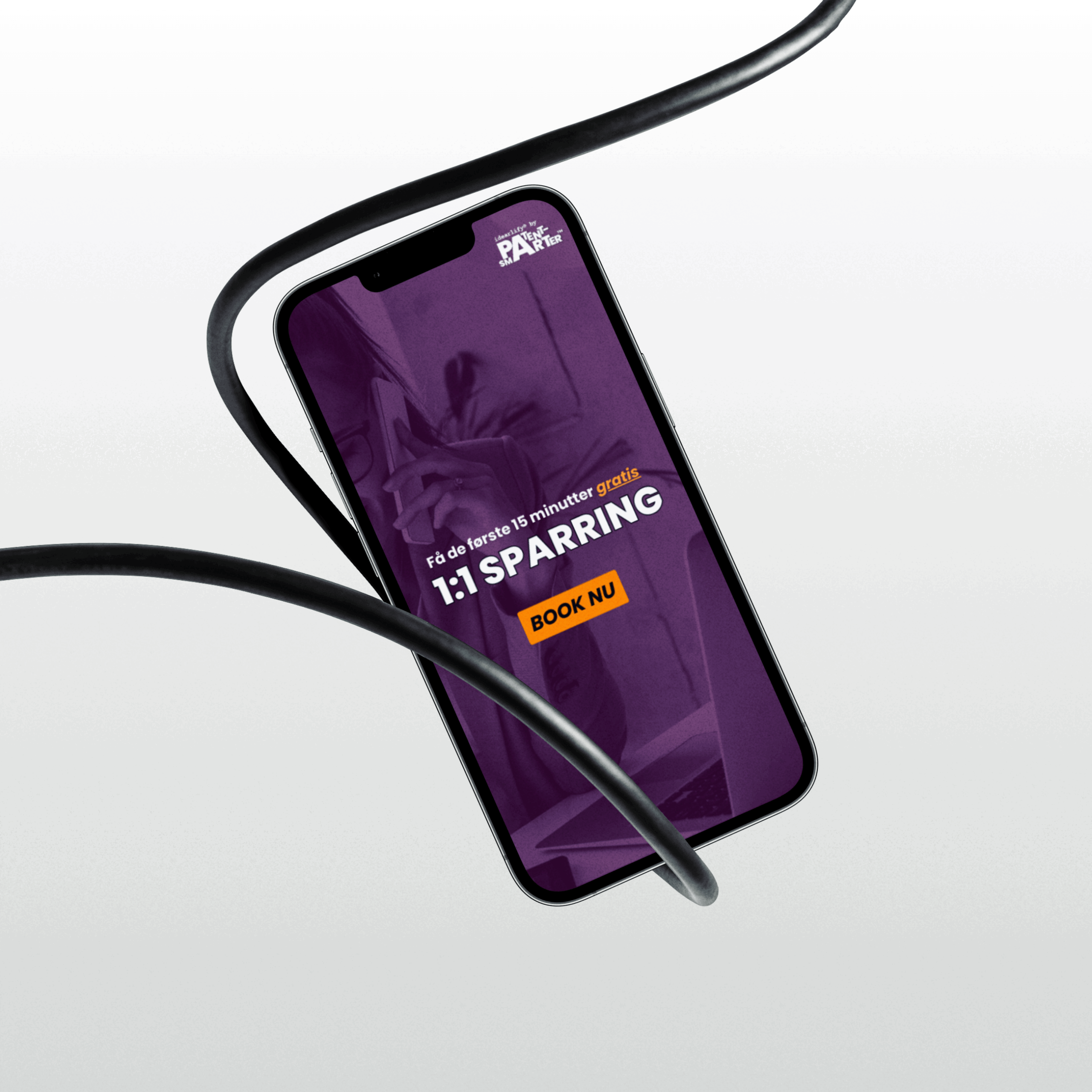 iphone 13 Pro hænger i en sort ledning, iphone viser en lilla baggrund, PATENTsmarter™ og idearlify® logo og overskriften »1:1 SPARRING« »BOOK NOW«, der peger på en 15-minutters gratis 1:1 sparringssession.