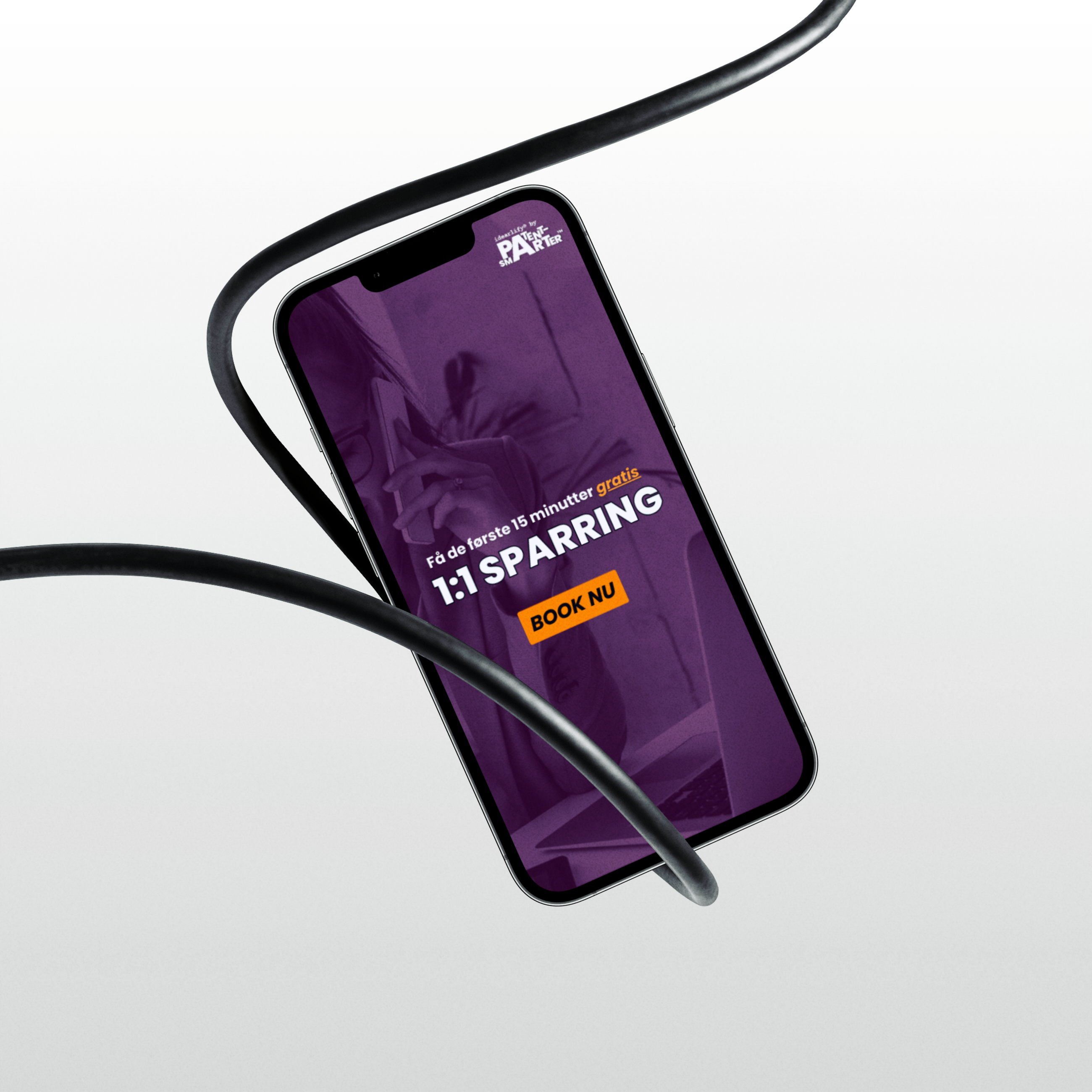iphone 13 Pro hænger i en sort ledning, iphone viser en lilla baggrund, PATENTsmarter™- og idearlify®-logo og overskriften "1:1 SPARRING" "BOOK NOW", der peger på en gratis 1:1 sparringssession på 15 minutter.